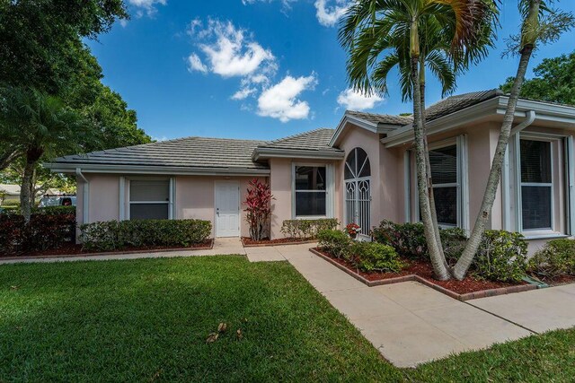 5166 SE Inkwood Way, Hobe Sound, FL 33455 - ranch-style house with a tiled roof, a front lawn, and stucco siding