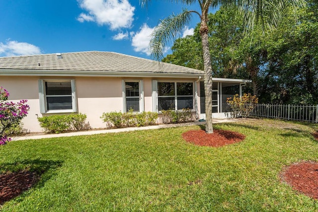 5166 SE Inkwood Way, Hobe Sound, FL 33455 - view of front facade with a sunroom, stucco siding, fence, and a front lawn