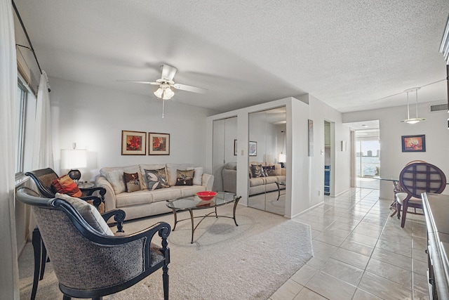 living area featuring visible vents, a ceiling fan, a textured ceiling, and light tile patterned flooring