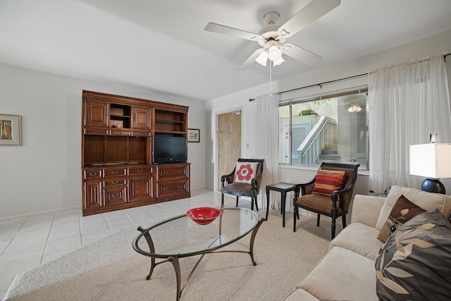 living area featuring baseboards, light tile patterned floors, and a ceiling fan