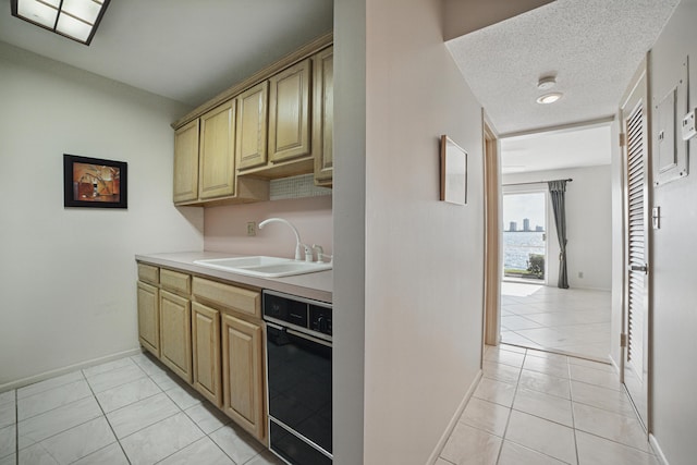 kitchen with baseboards, light tile patterned flooring, light countertops, and a sink