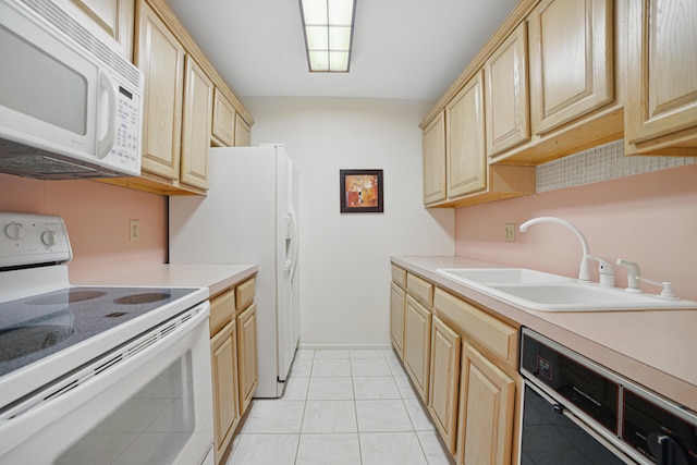 kitchen with light countertops, light brown cabinetry, a sink, and white appliances
