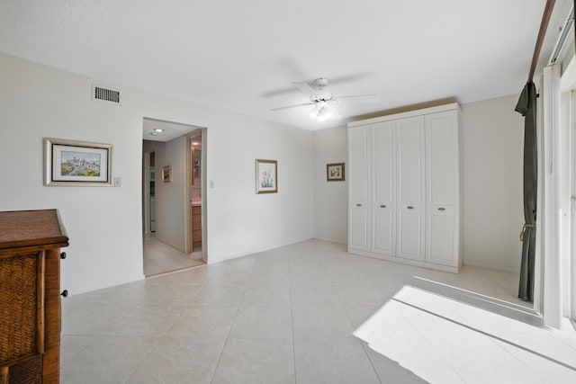 unfurnished bedroom featuring visible vents, light tile patterned floors, a ceiling fan, and a closet