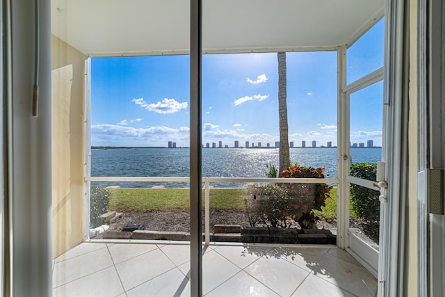 unfurnished sunroom featuring tile patterned floors, a water view, and plenty of natural light