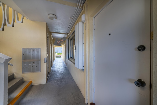 corridor with stairway, concrete floors, and mail area
