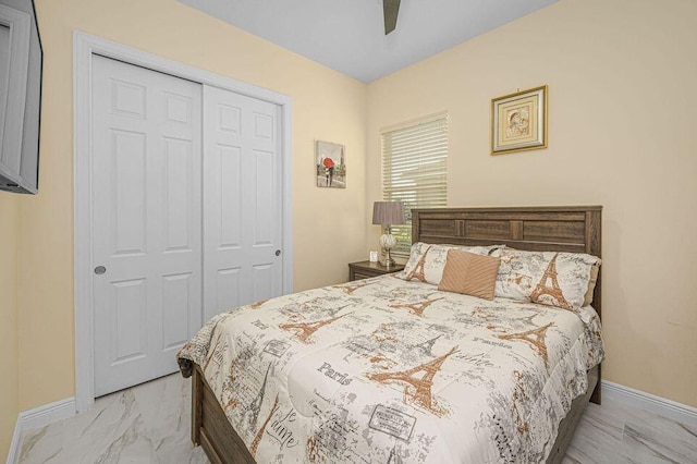 bedroom with a closet, baseboards, marble finish flooring, and ceiling fan