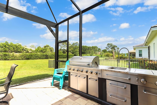 view of patio / terrace featuring a sink, exterior kitchen, and view of wooded area