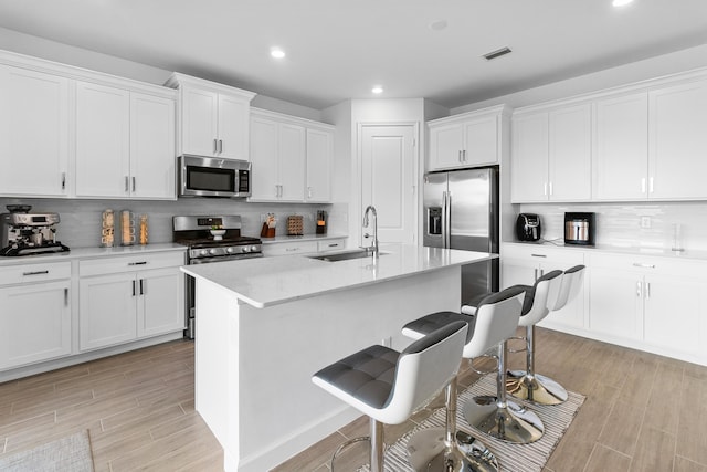 1218 Timber Reap Trl, The Acreage, FL 33470 - kitchen featuring recessed lighting, visible vents, a sink, a kitchen bar, and appliances with stainless steel finishes