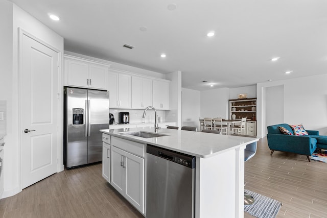 1218 Timber Reap Trl, The Acreage, FL 33470 - kitchen featuring light wood-style flooring, a sink, a center island with sink, white cabinetry, and appliances with stainless steel finishes