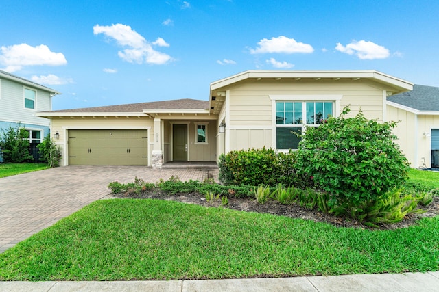 1218 Timber Reap Trl, The Acreage, FL 33470 - view of front of home with a front lawn, a garage, a shingled roof, board and batten siding, and decorative driveway