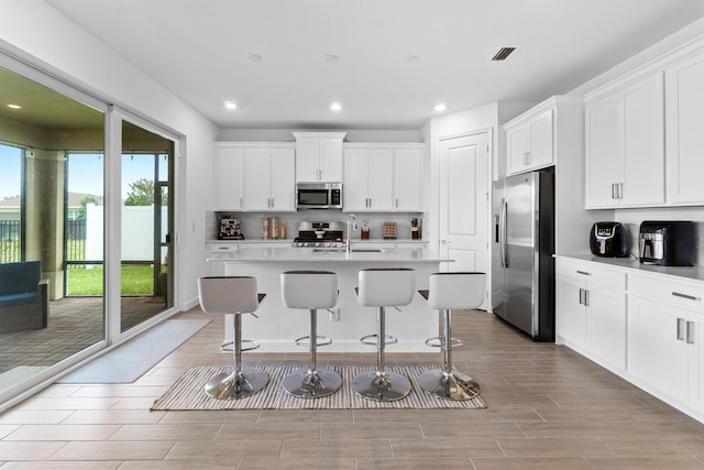 1218 Timber Reap Trl, The Acreage, FL 33470 - kitchen with stainless steel appliances, a sink, visible vents, recessed lighting, and a kitchen bar