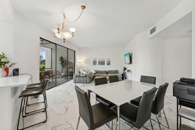 dining room with a textured ceiling, visible vents, marble finish floor, and an inviting chandelier