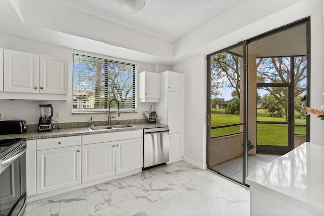 kitchen with appliances with stainless steel finishes, marble finish floor, a sink, and white cabinets