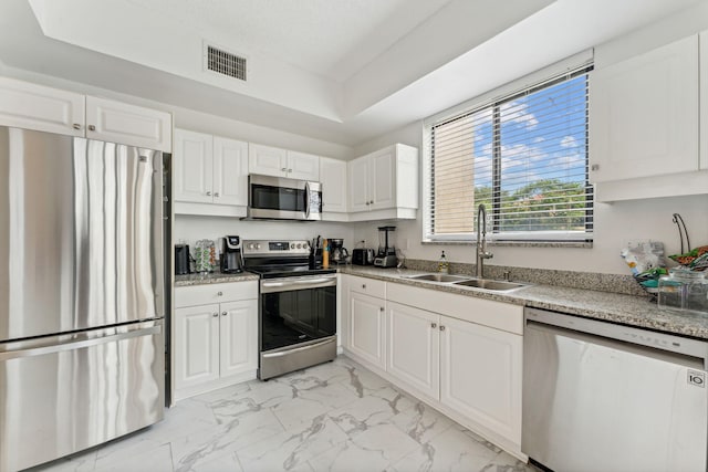 kitchen featuring visible vents, a sink, appliances with stainless steel finishes, white cabinetry, and marble finish floor