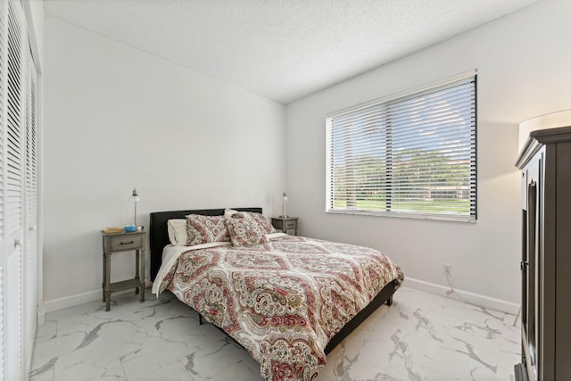 bedroom featuring marble finish floor, baseboards, and a textured ceiling