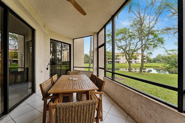 sunroom with a water view, a ceiling fan, and outdoor dining area