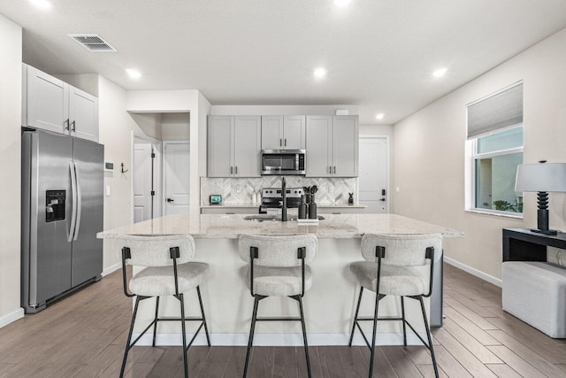 5612 Mentmore Dr, West Palm Beach, FL 33407 - kitchen with appliances with stainless steel finishes, a sink, light wood finished floors, tasteful backsplash, and baseboards