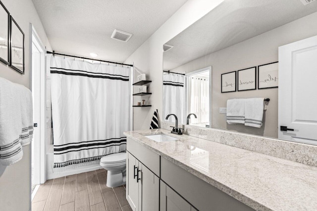 5612 Mentmore Dr, West Palm Beach, FL 33407 - bathroom featuring toilet, vanity, a textured ceiling, wood tiled floors, and shower / bath combo with shower curtain