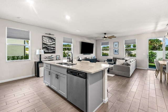 5612 Mentmore Dr, West Palm Beach, FL 33407 - kitchen with stainless steel dishwasher, a sink, baseboards, wood tiled floors, and healthy amount of natural light