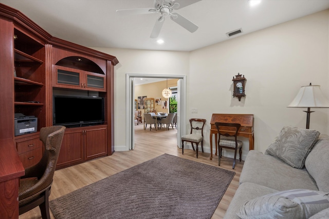 living area with light wood-style floors, baseboards, a ceiling fan, and visible vents