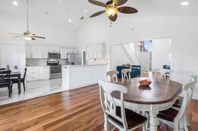 12820 Smithdale Pl, Boca Raton, FL 33428 - dining area with stairs, light wood-style floors, visible vents, high vaulted ceiling, and ceiling fan with notable chandelier