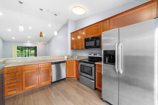 kitchen with a sink, stainless steel appliances, decorative light fixtures, brown cabinets, and light wood finished floors