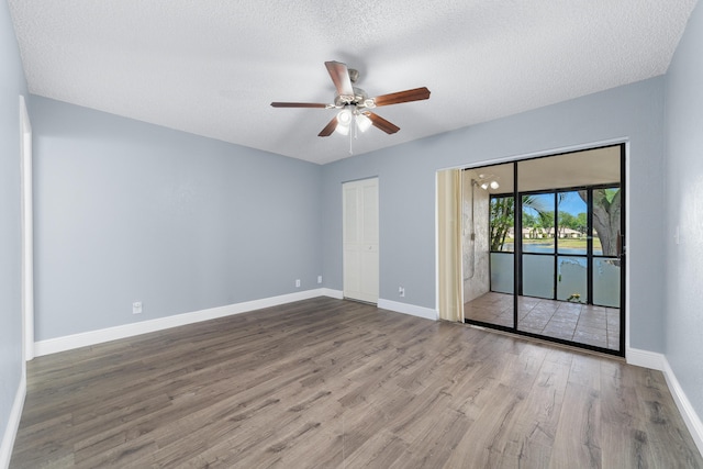 spare room with a textured ceiling, wood finished floors, ceiling fan, and baseboards
