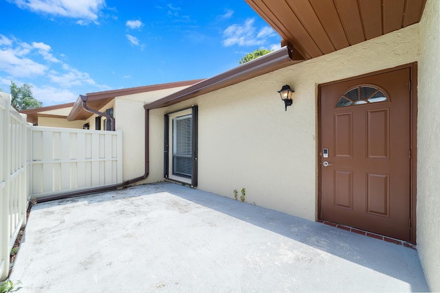 entrance to property featuring a patio, stucco siding, and fence