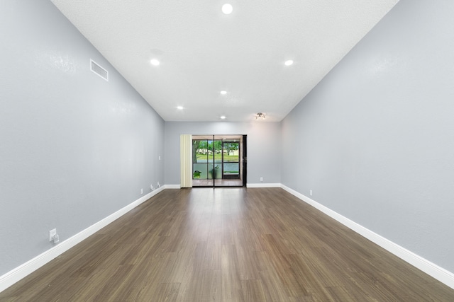 empty room featuring visible vents, baseboards, and dark wood finished floors