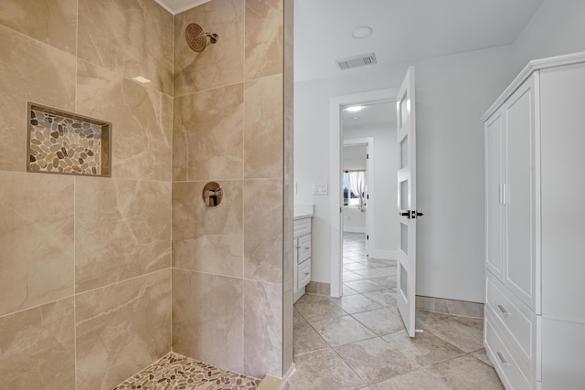 bathroom with baseboards, tile patterned flooring, visible vents, and tiled shower