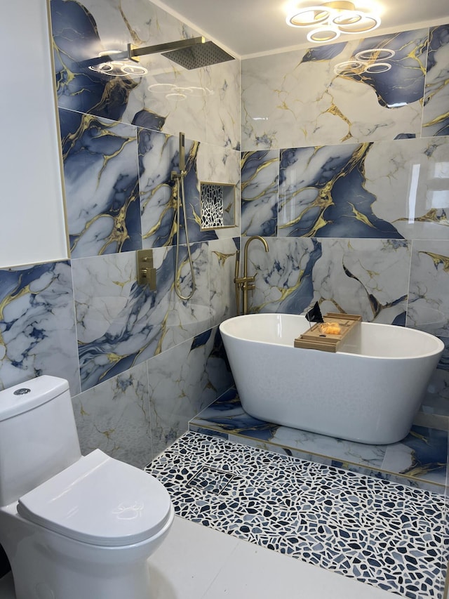 bathroom with a marble finish shower, a freestanding bath, toilet, tile walls, and stone wall