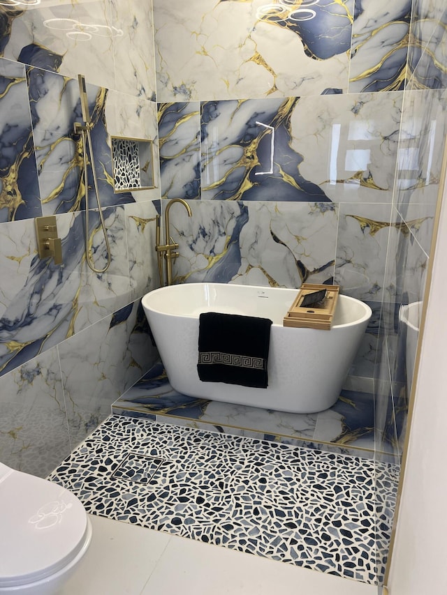 full bathroom with marble finish floor, tile walls, a soaking tub, and toilet