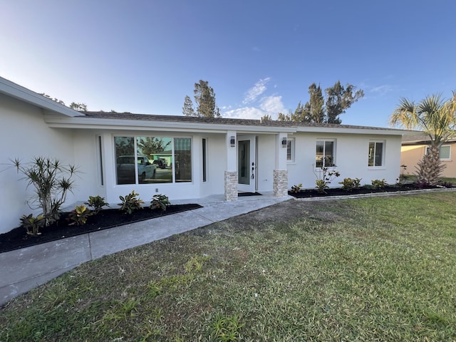 ranch-style home with stucco siding and a front lawn