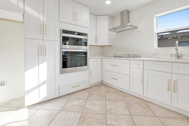 kitchen with black electric cooktop, a sink, wall chimney range hood, light tile patterned floors, and double oven