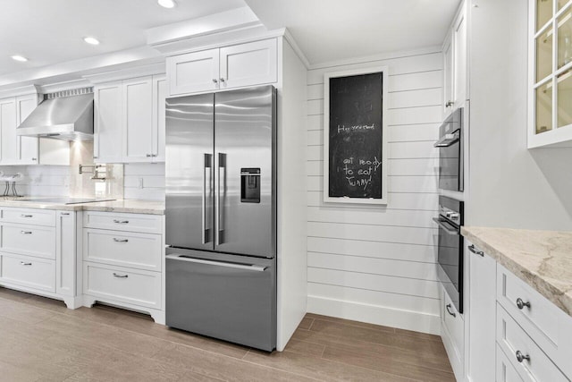 2917 S Ocean Blvd Unit 104, Highland Beach, FL 33487 - kitchen with high end refrigerator, wall chimney exhaust hood, white cabinetry, recessed lighting, and light wood finished floors