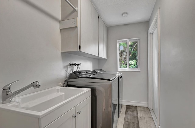 2416 NW 32nd St, Boca Raton, FL 33431 - washroom featuring washing machine and dryer, cabinet space, a textured ceiling, light wood-style flooring, and baseboards