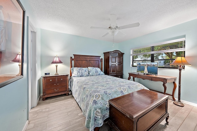 bedroom with a textured ceiling, ceiling fan, baseboards, and wood tiled floor