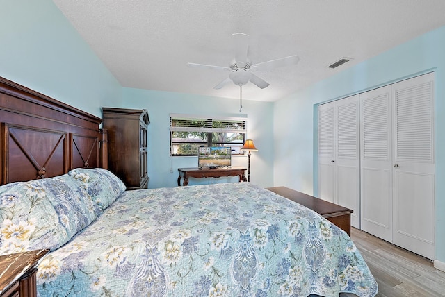 bedroom featuring light wood-style flooring, a closet, visible vents, and ceiling fan