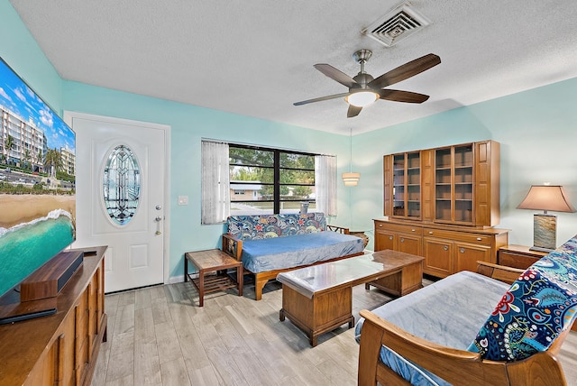 bedroom featuring visible vents, ceiling fan, light wood-type flooring, and a textured ceiling