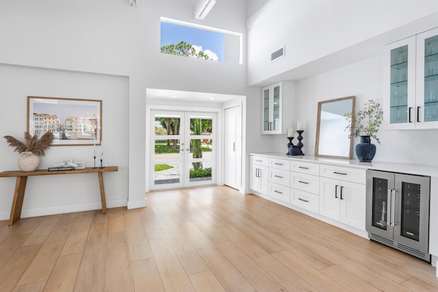 654 Lakewoode Cir W, Delray Beach, FL 33445 - foyer featuring beverage cooler, light wood-style flooring, and a towering ceiling