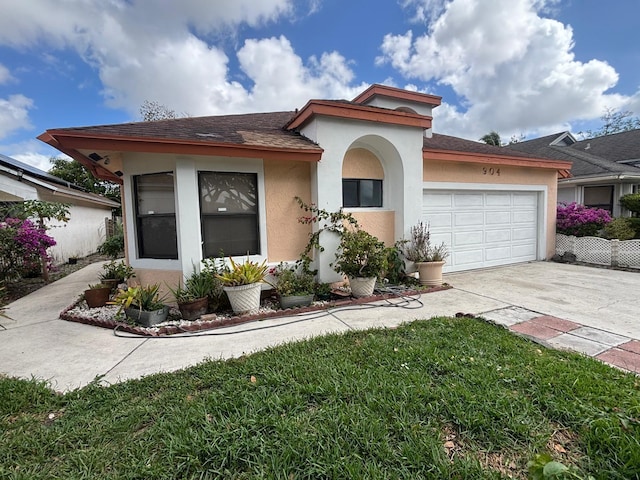 mediterranean / spanish house featuring a garage, a front yard, driveway, and stucco siding