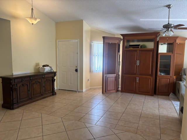 interior space featuring a textured ceiling, light tile patterned flooring, and ceiling fan