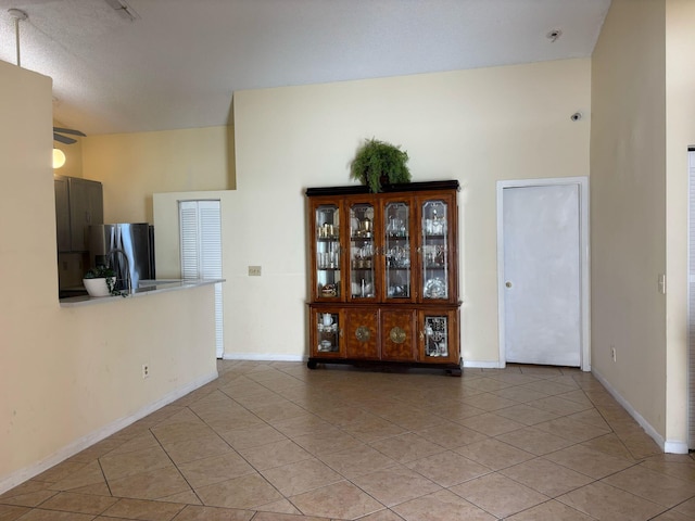 interior space featuring a high ceiling, light tile patterned floors, and baseboards
