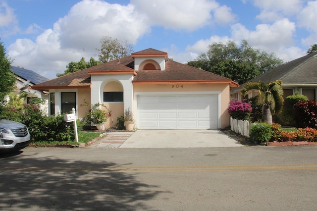 mediterranean / spanish-style home with a garage, stucco siding, and driveway