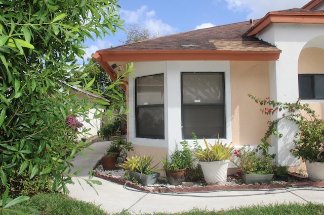 view of side of home with roof with shingles and stucco siding