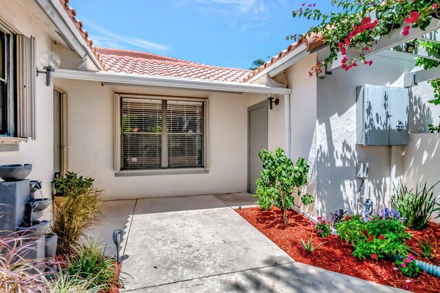 21687 Cromwell Cir, Boca Raton, FL 33486 - doorway to property with stucco siding, a tile roof, and a patio area