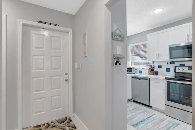 21687 Cromwell Cir, Boca Raton, FL 33486 - kitchen featuring white cabinets, stainless steel appliances, tasteful backsplash, baseboards, and light countertops