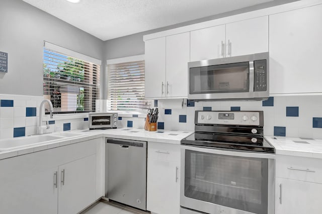 21687 Cromwell Cir, Boca Raton, FL 33486 - kitchen featuring tasteful backsplash, a textured ceiling, a sink, stainless steel appliances, and white cabinetry