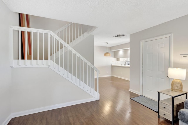 entrance foyer with stairway, wood-type flooring, visible vents, and baseboards