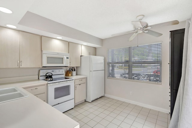 kitchen featuring baseboards, white appliances, light countertops, ceiling fan, and a sink